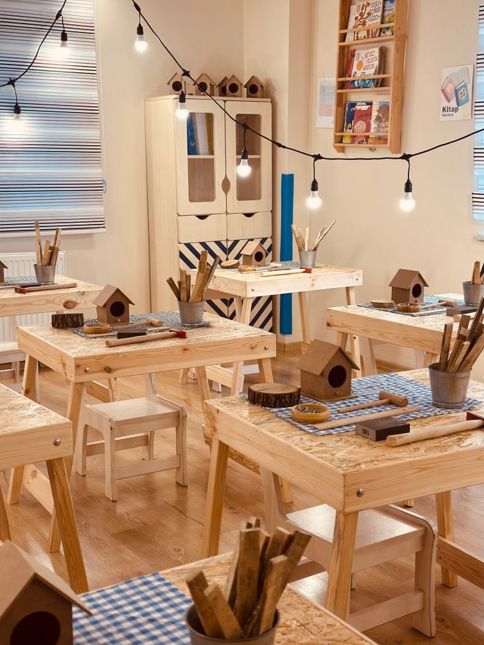 who-we-are Inviting classroom setup featuring craft tables, birdhouses, and warm lighting, perfect for imaginative children's activities.