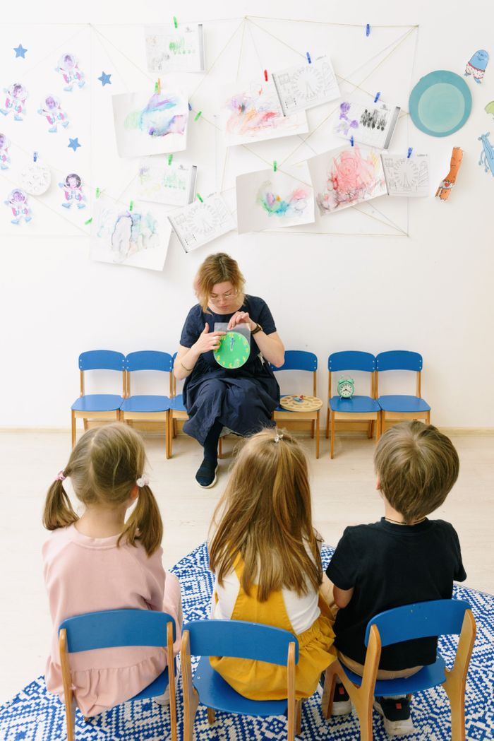 our-story Teacher engages children during storytime in a colorful preschool classroom.