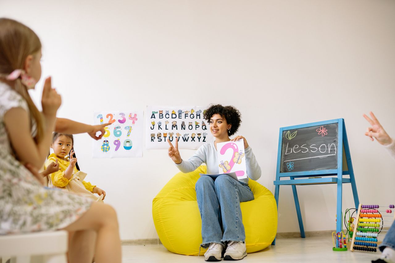 services-02 Teacher engaging young students in a fun and educational preschool setting.